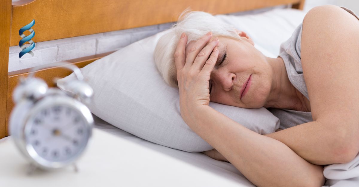 Elderly woman in bed, looking distressed with hand on forehead, alarm clock beside her