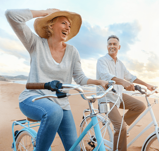 couple is riding bicycles on a sandy beach