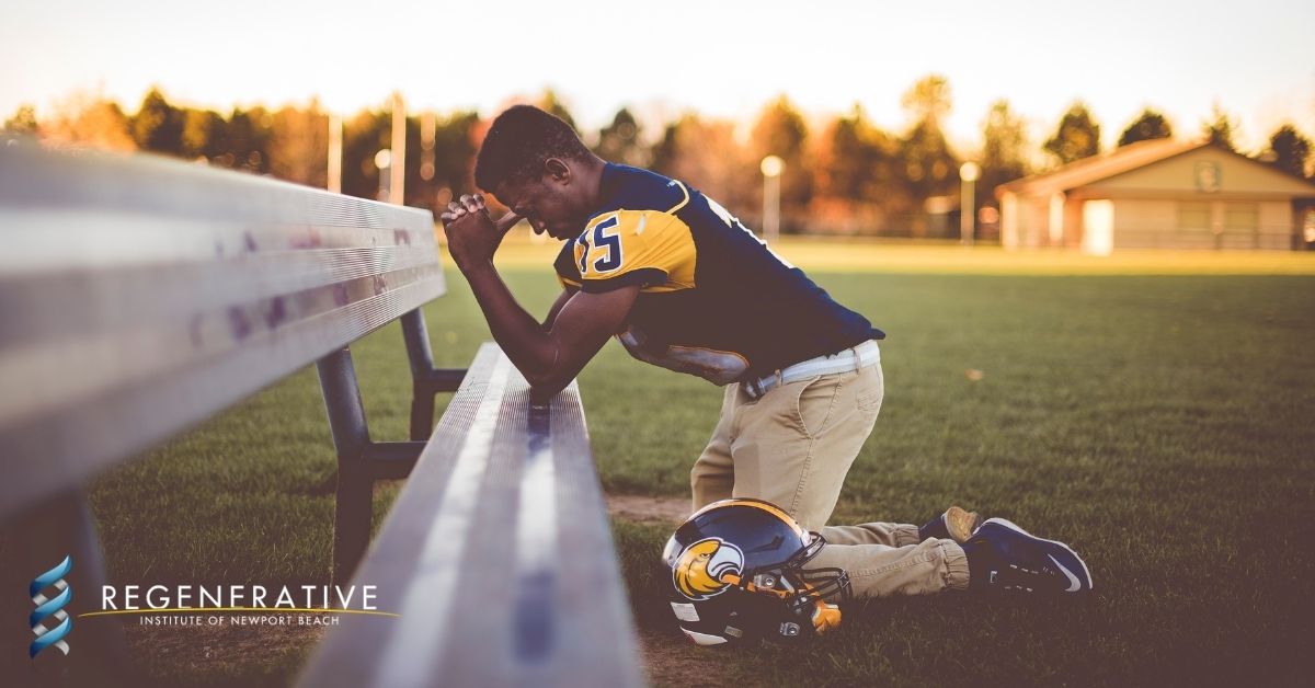 Football player kneeling on bench in pain