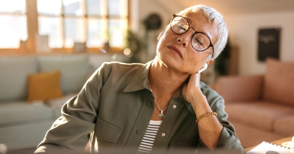 woman sitting at her desk, experiencing neck pain