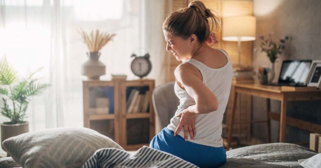 A woman experiencing back pain near her hip