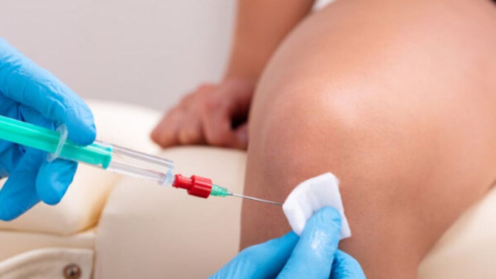 A person receiving a knee injection, seated and focused, with a healthcare professional administering the procedure.