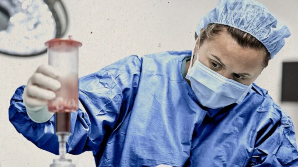 A woman in a blue scrub suit confidently holds a syringe, ready for a medical procedure.