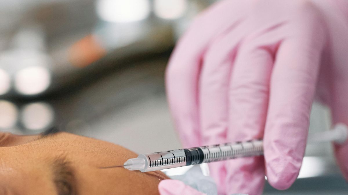 A close-up of an individual undergoing a forehead botox injection, highlighting the medical procedure in progress.