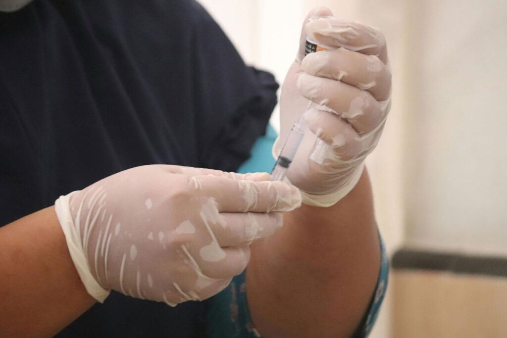 A healthcare worker in a hospital, wearing gloves and a mask, focused on patient care and safety protocols