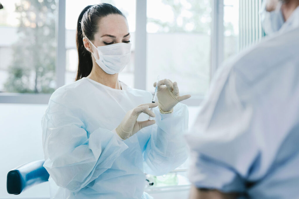 A woman wearing a surgical mask and gloves engages in conversation with a man, emphasizing health and safety measures